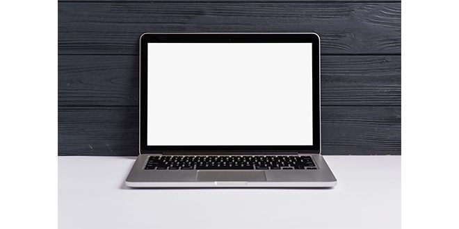An open laptop with blank white screen on white desk against black wooden backdrop Photo